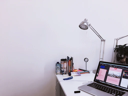 A clean desk workspace with a laptop displaying a web design and notes showing pricing options.