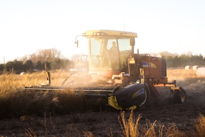 Modern farm machinery working in a sunlit field during harvest.