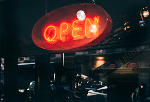 A glowing neon sign illuminating a storefront on a busy Ahmedabad street at night.