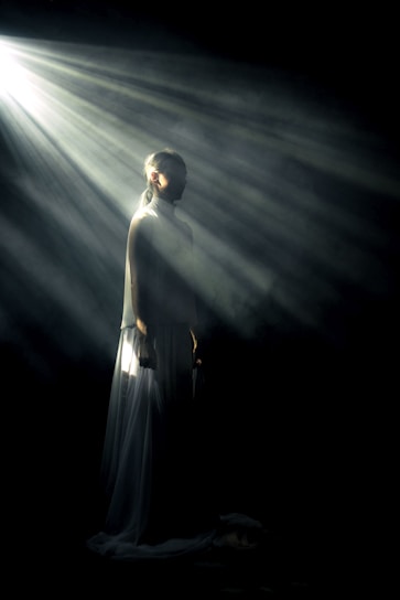 A shadowy, elegant silhouette of a person standing in a dimly lit urban alley, embodying mystery and transformation.