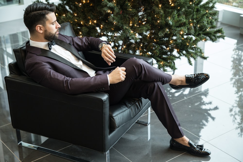 man sitting on black sofa chair while watching watch