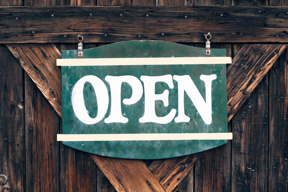 A large green âopenâ signboard on an old wooden door