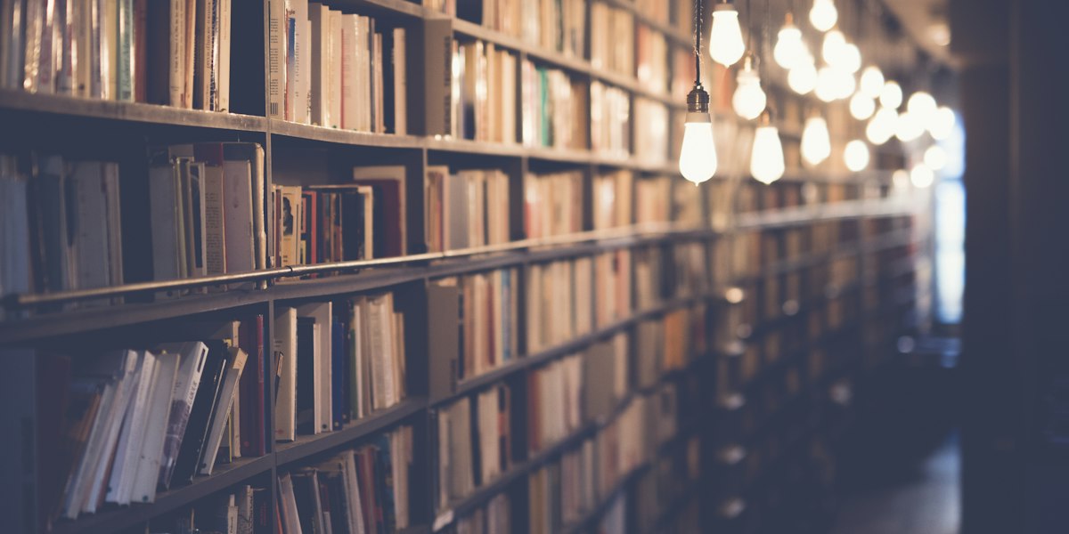 Book Adaptations: Why Hollywood Keeps Turning to Literature 2 Open books stacked in a library representing Hollywood's literary IP pipeline for film and TV adaptation