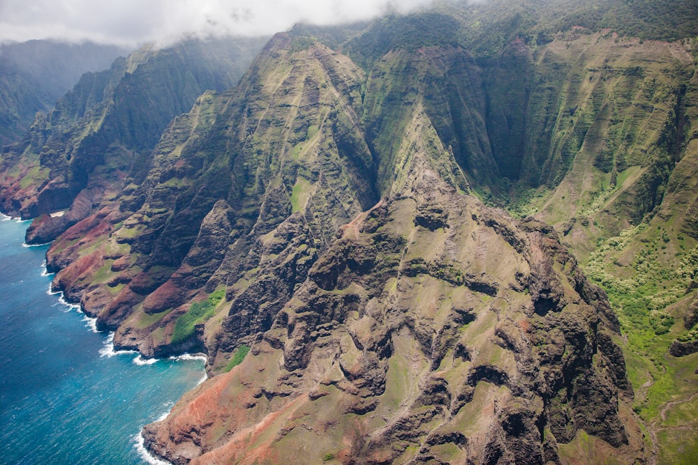 green and brown mountain near body of water in aerial photography