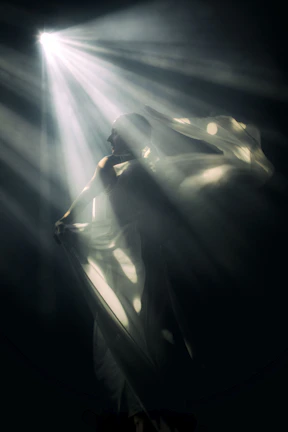 An ethereal figure bathed in warm gold, standing against a swirling indigo cosmic backdrop.