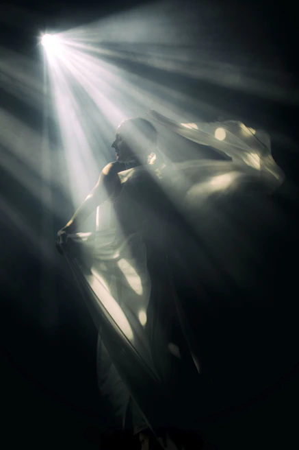 Atmospheric silhouette of a woman draped in flowing fabric, bathed in gentle purple light