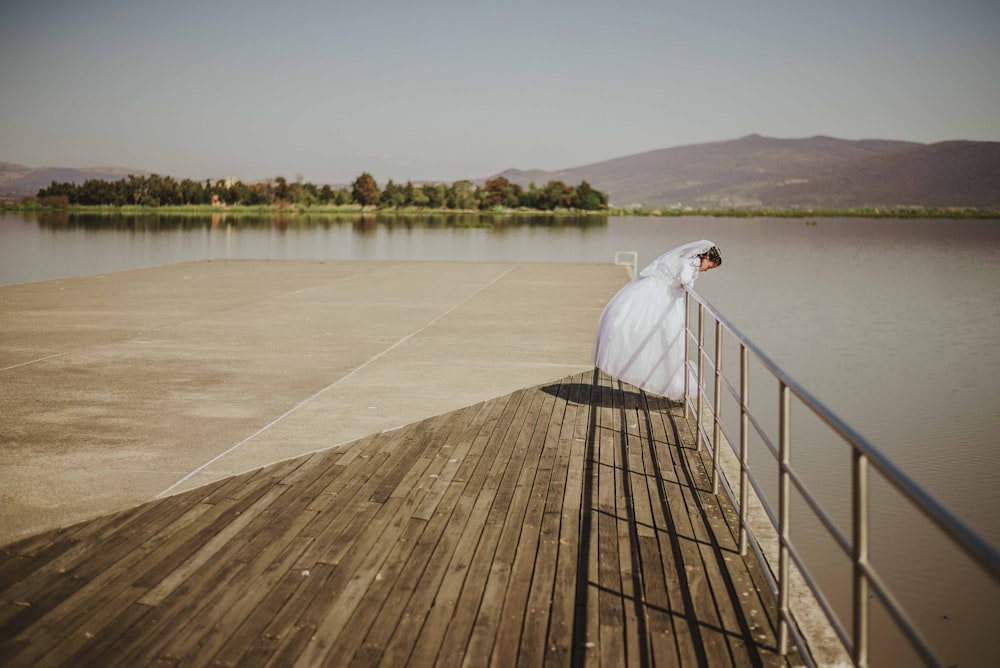 Frau im Brautkleid schaut auf Gewässer