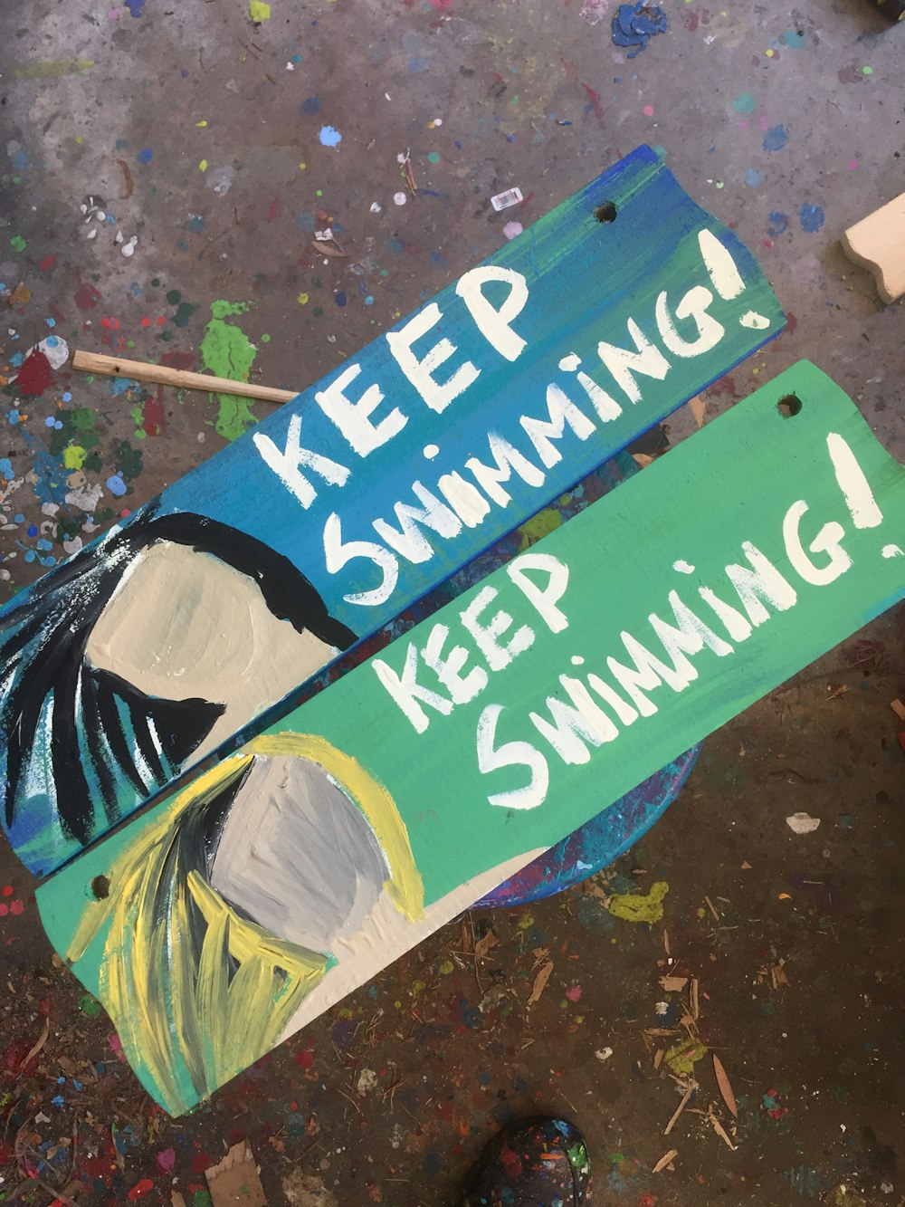 Colorful pieces of wood painted with blank faces that say "Keep swimming!"