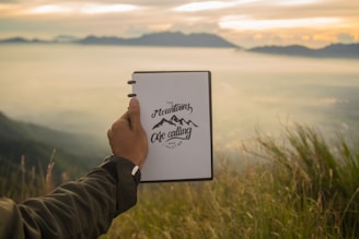 A close-up of a handcrafted notebook resting on a wooden table with the Himalayan mountains softly blurred in the background.