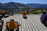 Guests relaxing on a wooden deck overlooking the Smoky Mountains, with cozy lodging buildings in the background.
