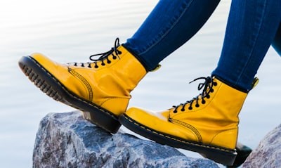 person wearing yellow doc martens airwair boots on gray rock boots teams background