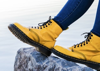 person wearing yellow Doc Martens Airwair boots on gray rock