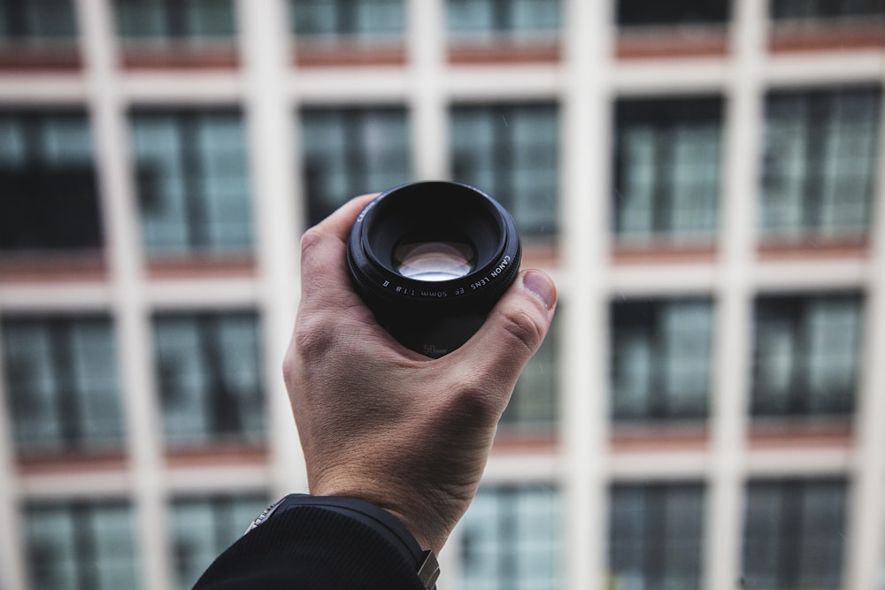 person holding black camera zoom lens selective focus photography