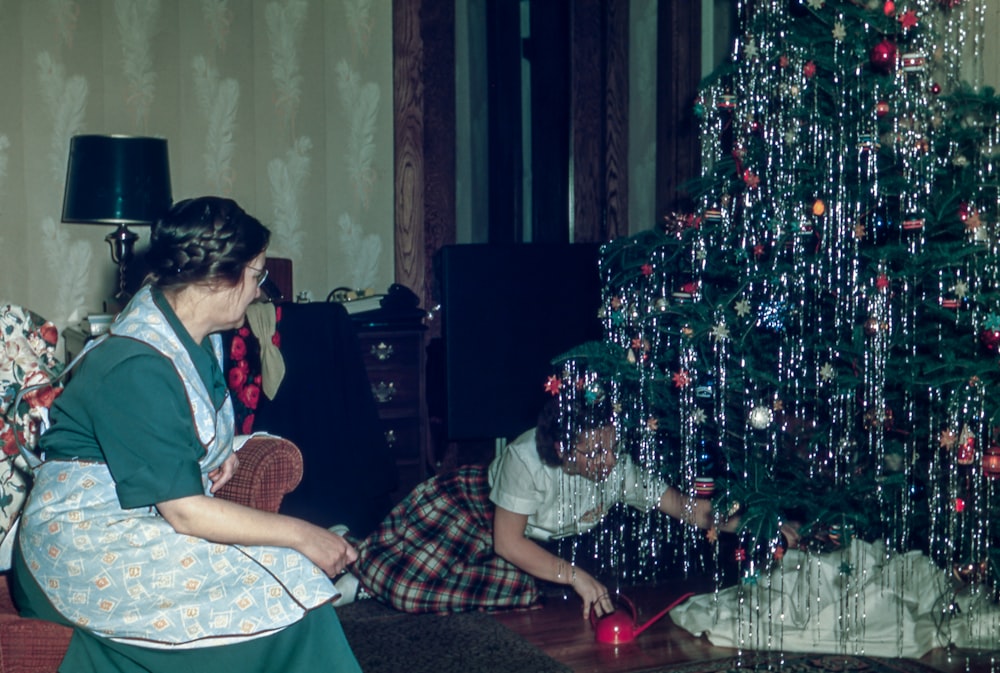 woman sitting under Christmas tree