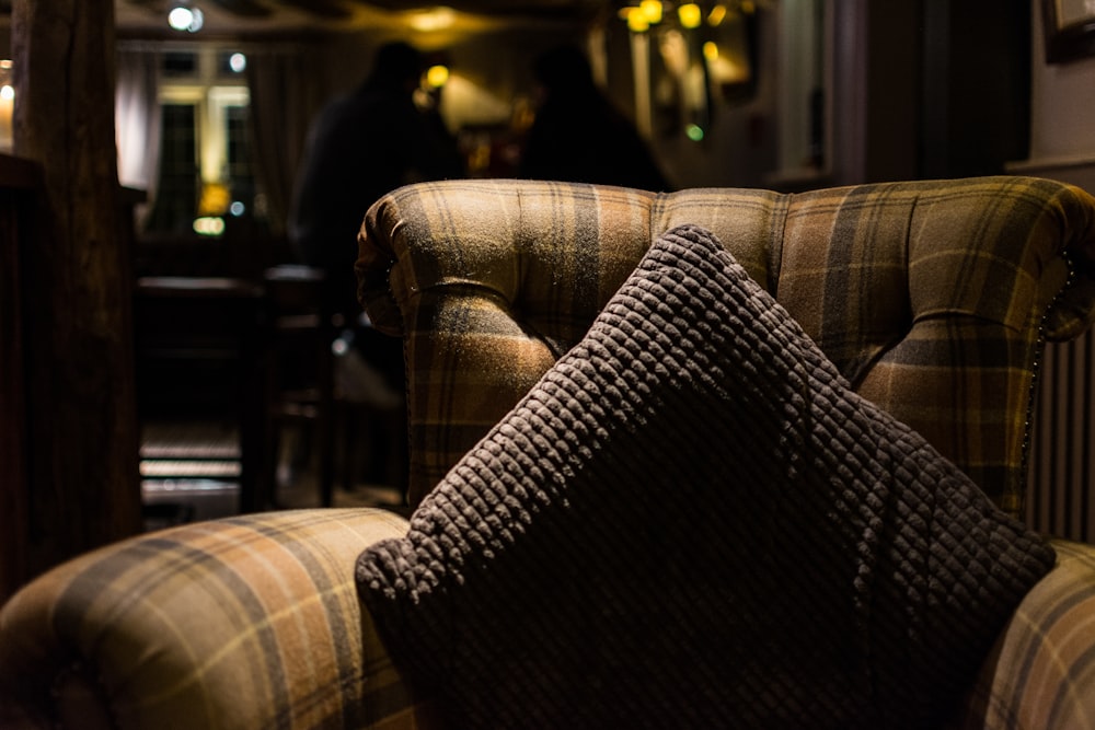 closeup photo of gray throw pillow on tufted sofa chair