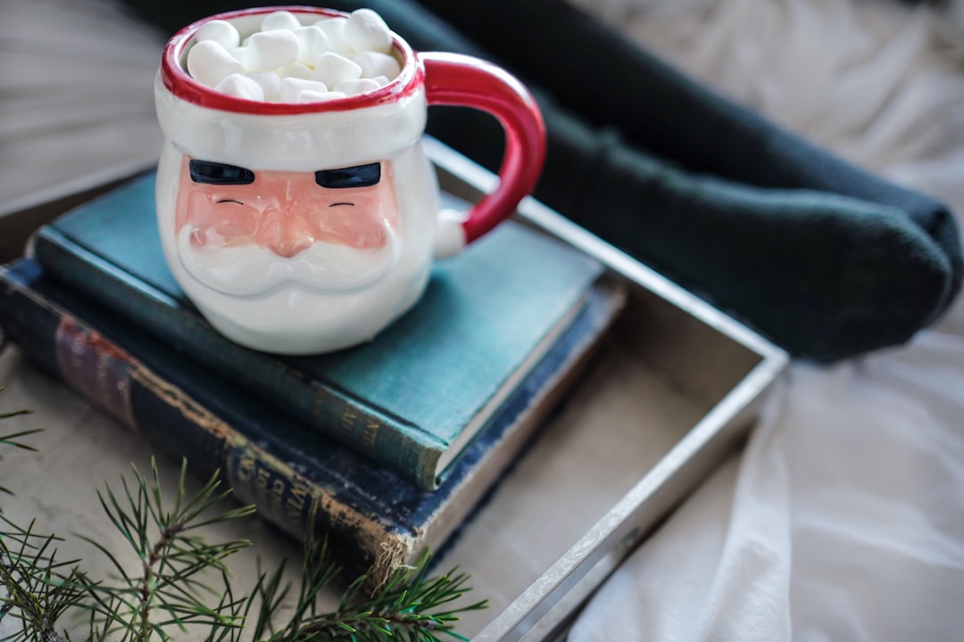 white and red ceramic mug on books