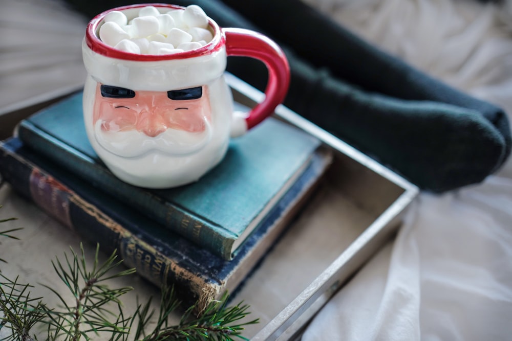 white and red ceramic mug on books