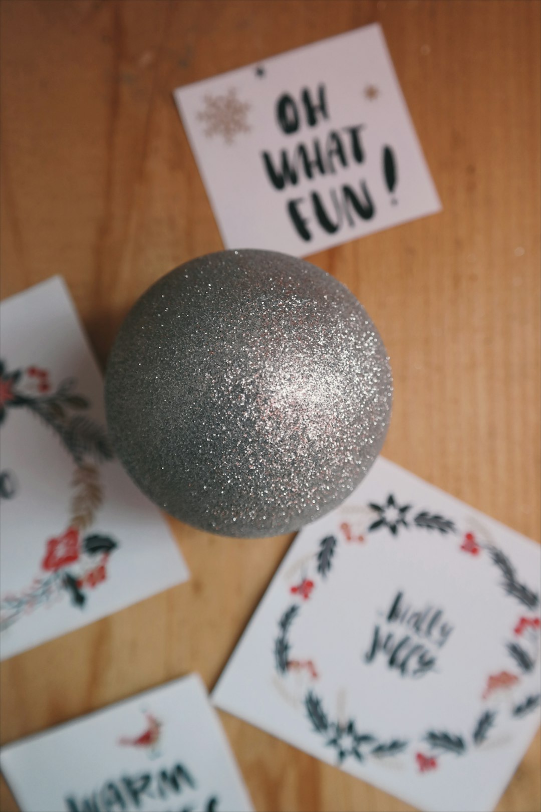 A gray Christmas ornament sitting on the floor next to little notes.