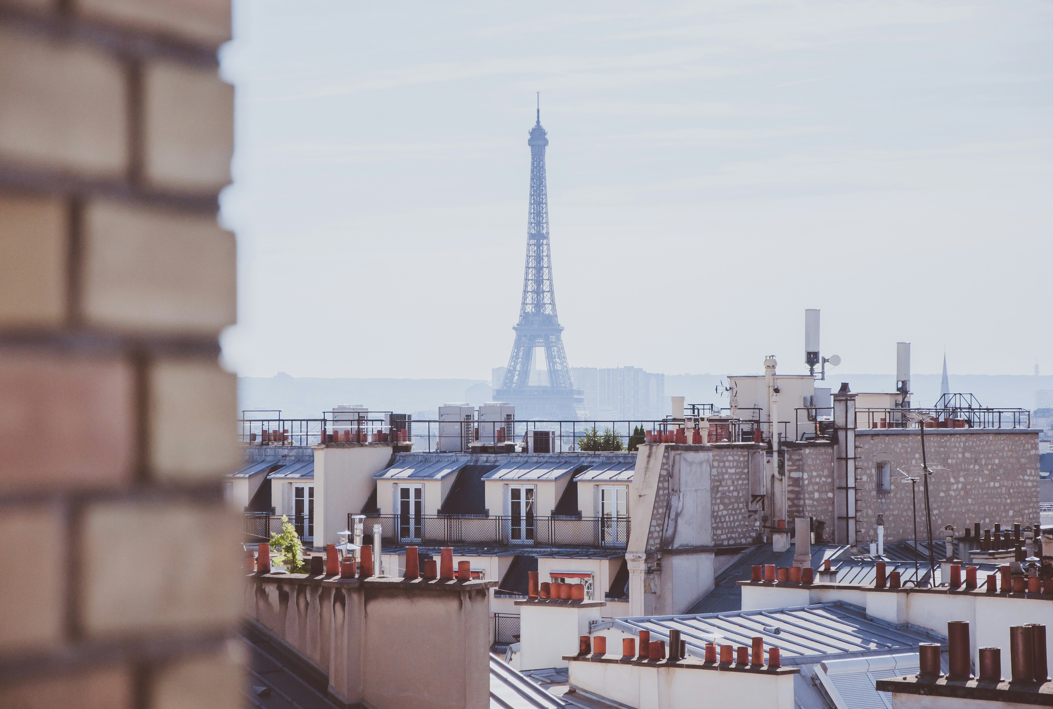 A rooftop view of brick chimney, buildings, and the Eiffel Tower in Paris, France.