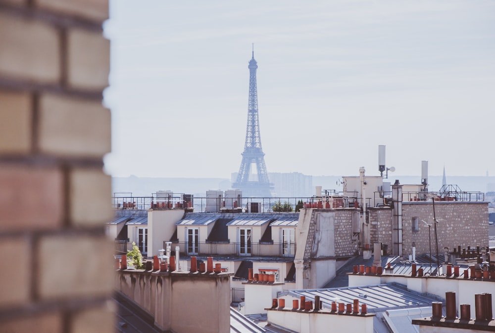 A rooftop view of brick chimney, buildings, and the Eiffel Tower in Paris, France.