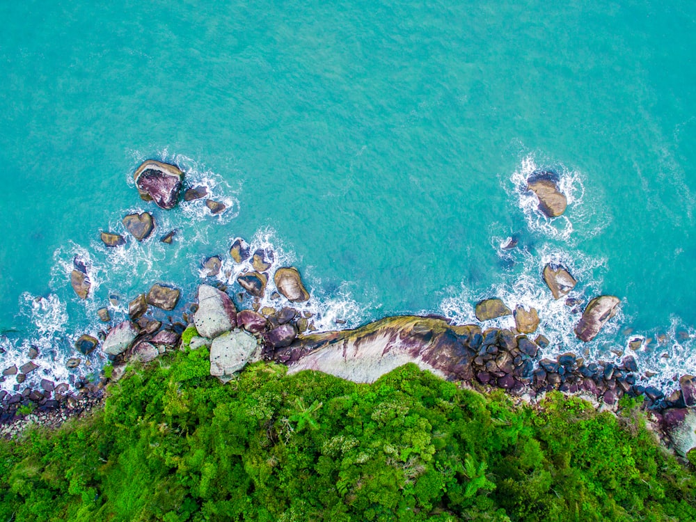 green and gray cliff near body of water in high angle photography