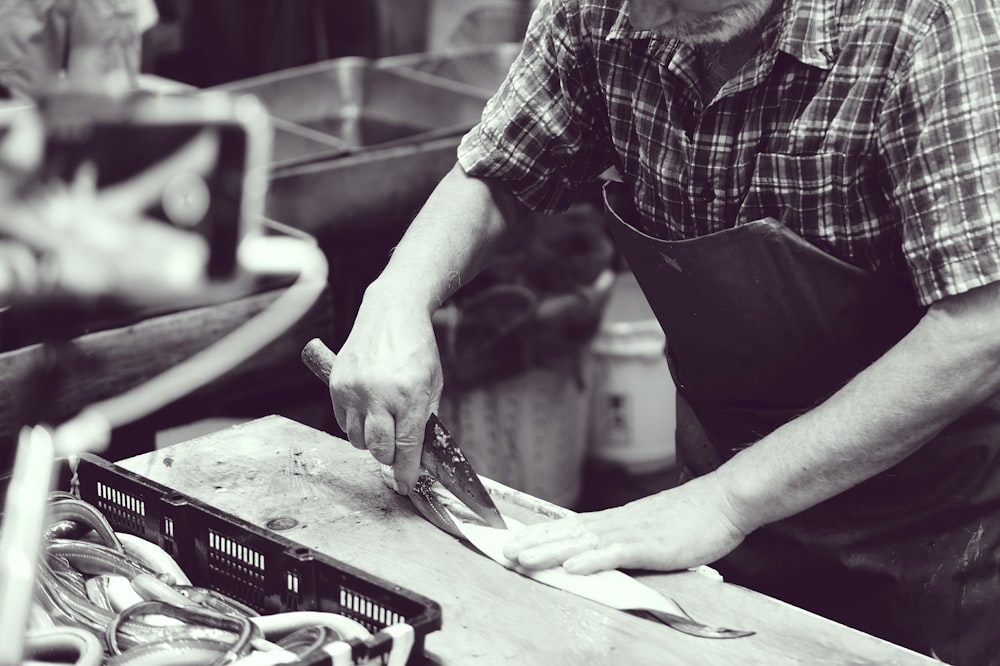 grayscale photography of man using knife