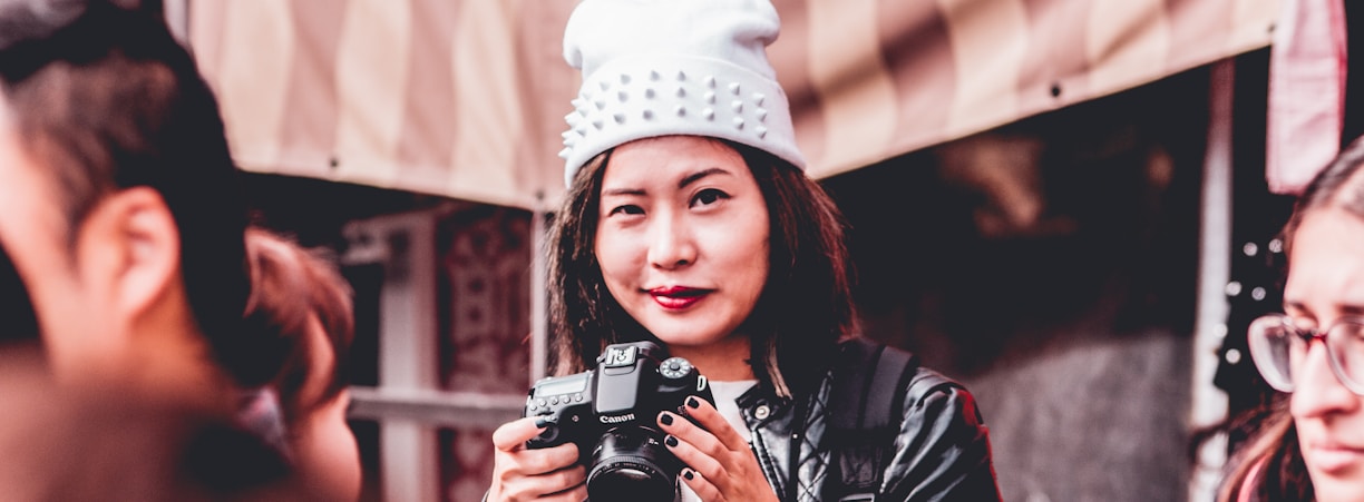 woman in black leather jacket holding DSLR camera