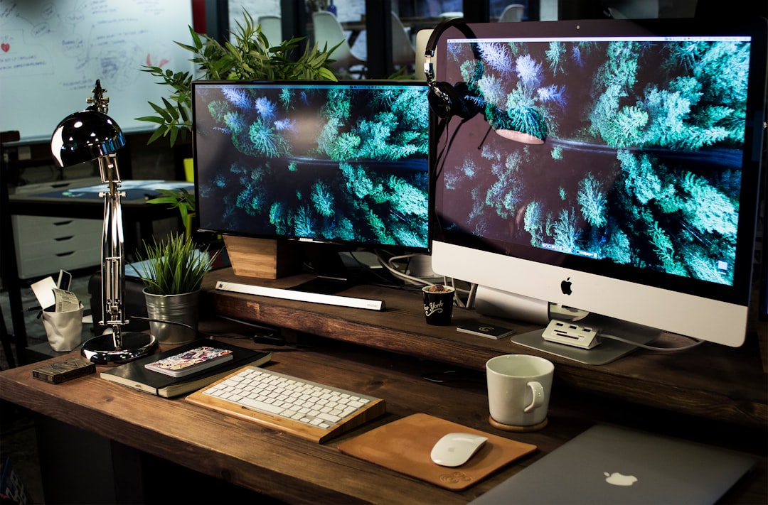 two computer monitors turned on with the same wallpaper, A simple shot of one of our office workspaces, Bristol UK.