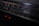 A close-up view of a vintage stereo radio cassette recorder. The focus is on the frequency display, which includes various numbers and units such as 540, 600, and 120m. Two small red indicator lights are glowing beneath the display, hinting at the device being powered on.