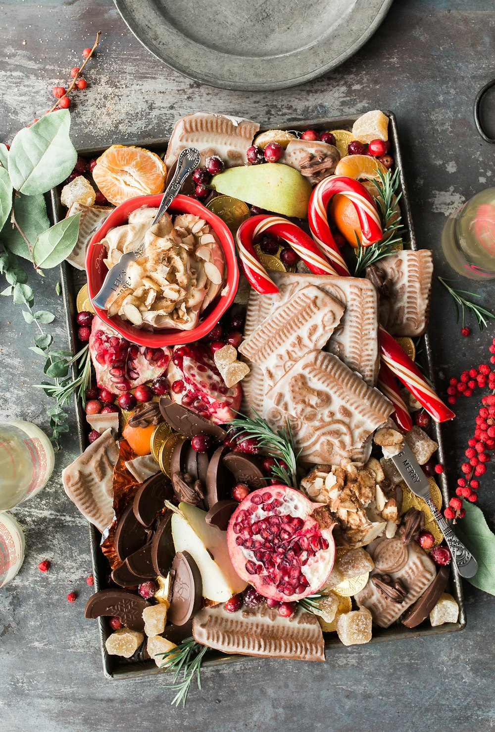 variety of sliced fruits, cookies, and chocolates on gray steel tray