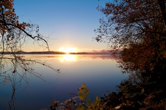 Sunrise over a serene lake surrounded by autumn trees