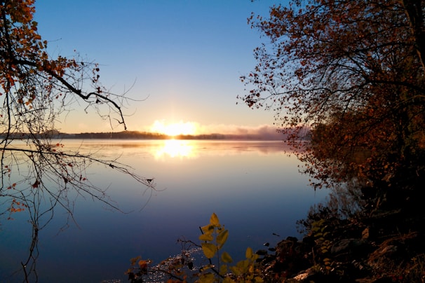 Sunrise over a serene lake surrounded by autumn trees