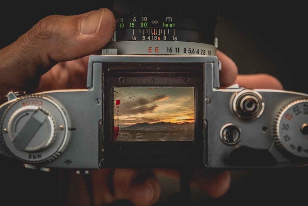 Persona che tiene la macchina fotografica grigia della pellicola