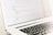 A close-up of a laptop displaying lines of HTML or programming code on its screen. The focus is on the code, with a shallow depth of field that blurs the background. The laptop is placed on a light-colored surface with its keyboard partially visible.