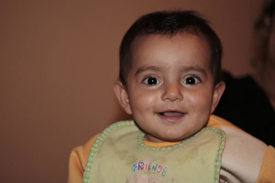 A smiling baby enjoying soft snacks in a bright, cozy kitchen setting.