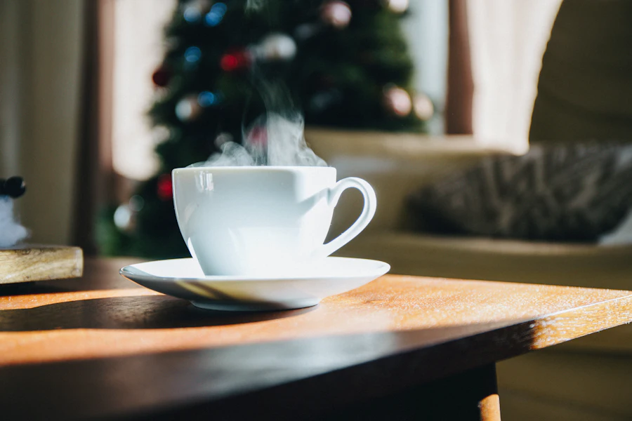 A warm mug in front of a lit Christmas tree
