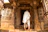 A smiling middle-aged woman standing near the temple entrance with traditional attire.