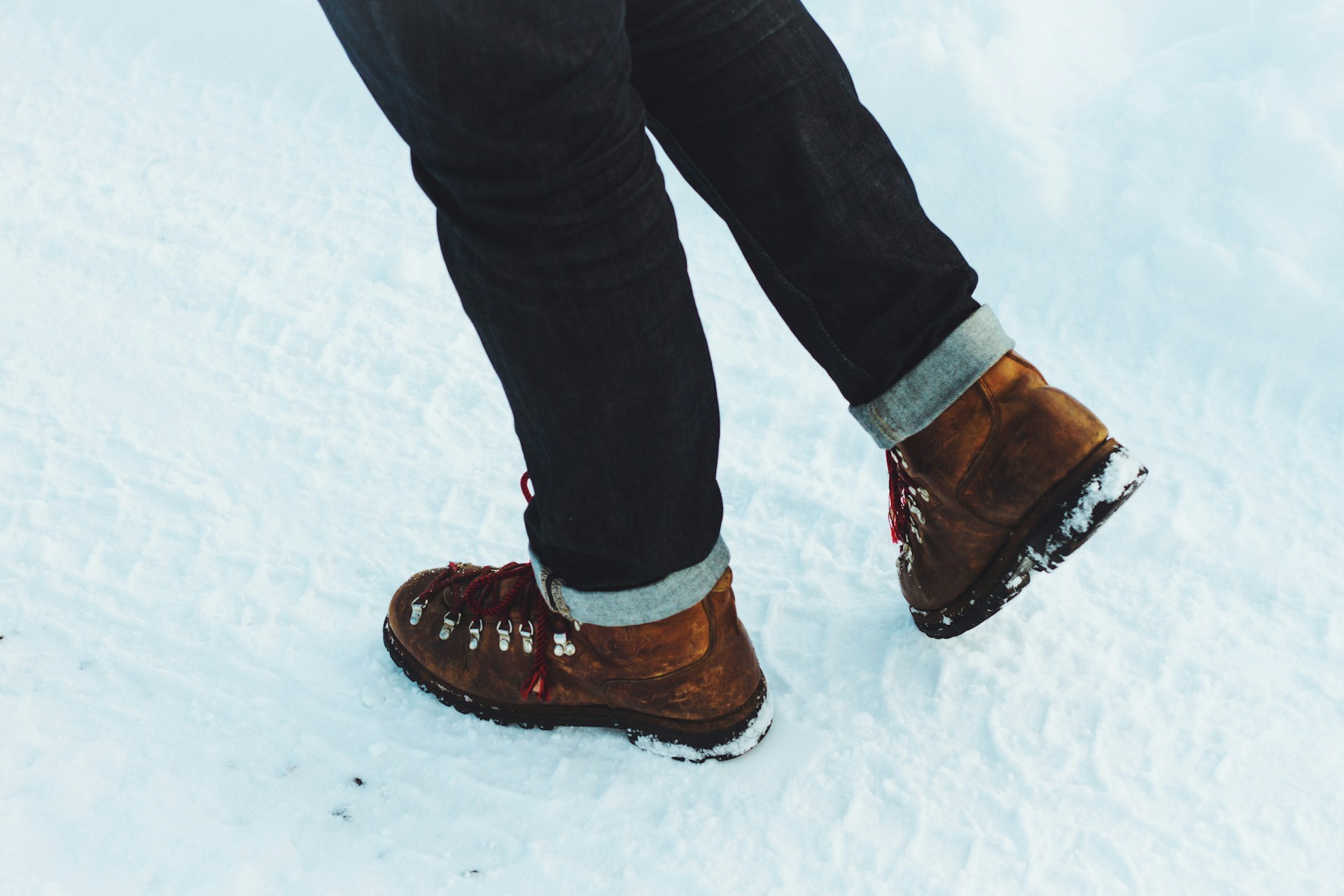 An adventurer wearing aeroboot boots while hiking through a snowy landscape, demonstrating durability and performance.