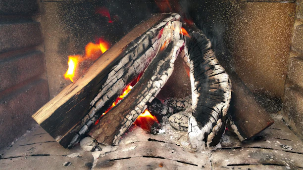 Close-up of a clean, well-maintained fireplace hearth with glowing embers inside.