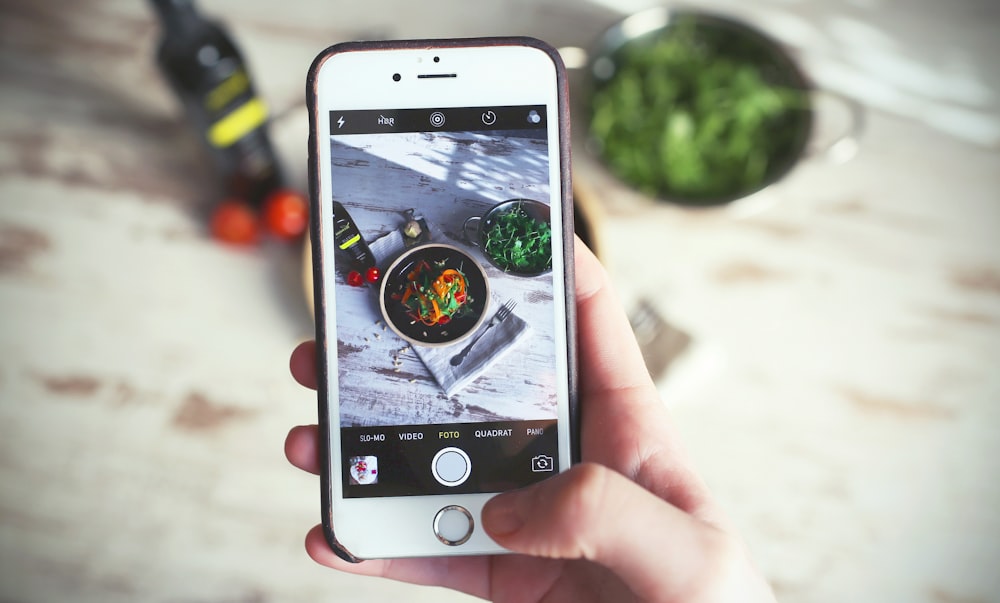 은색 iPhone 6을 사용하여 야채 음식을 캡처하는 사람