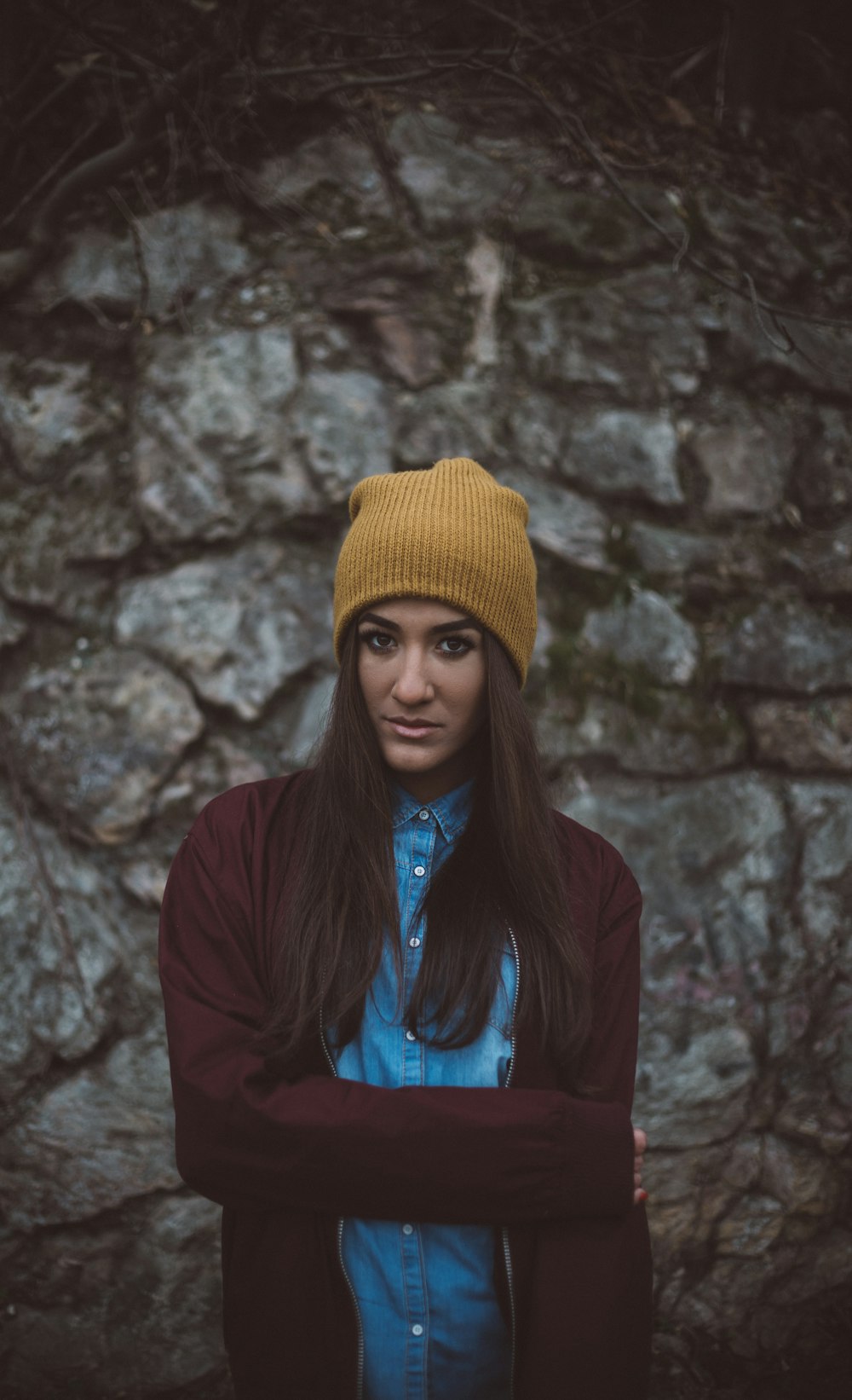 femme portant un bonnet en tricot marron debout devant un mur gris