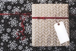 gold and white gift box on white and black fair-isle print surface