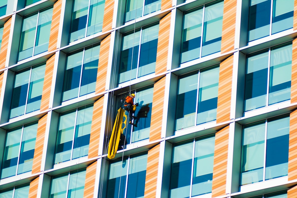 person climbing on curtain wall building