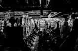 A dimly lit casino filled with rows of slot machines, some occupied by people. The machines' lights contrast with the dark surroundings, creating a vibrant yet subdued atmosphere.