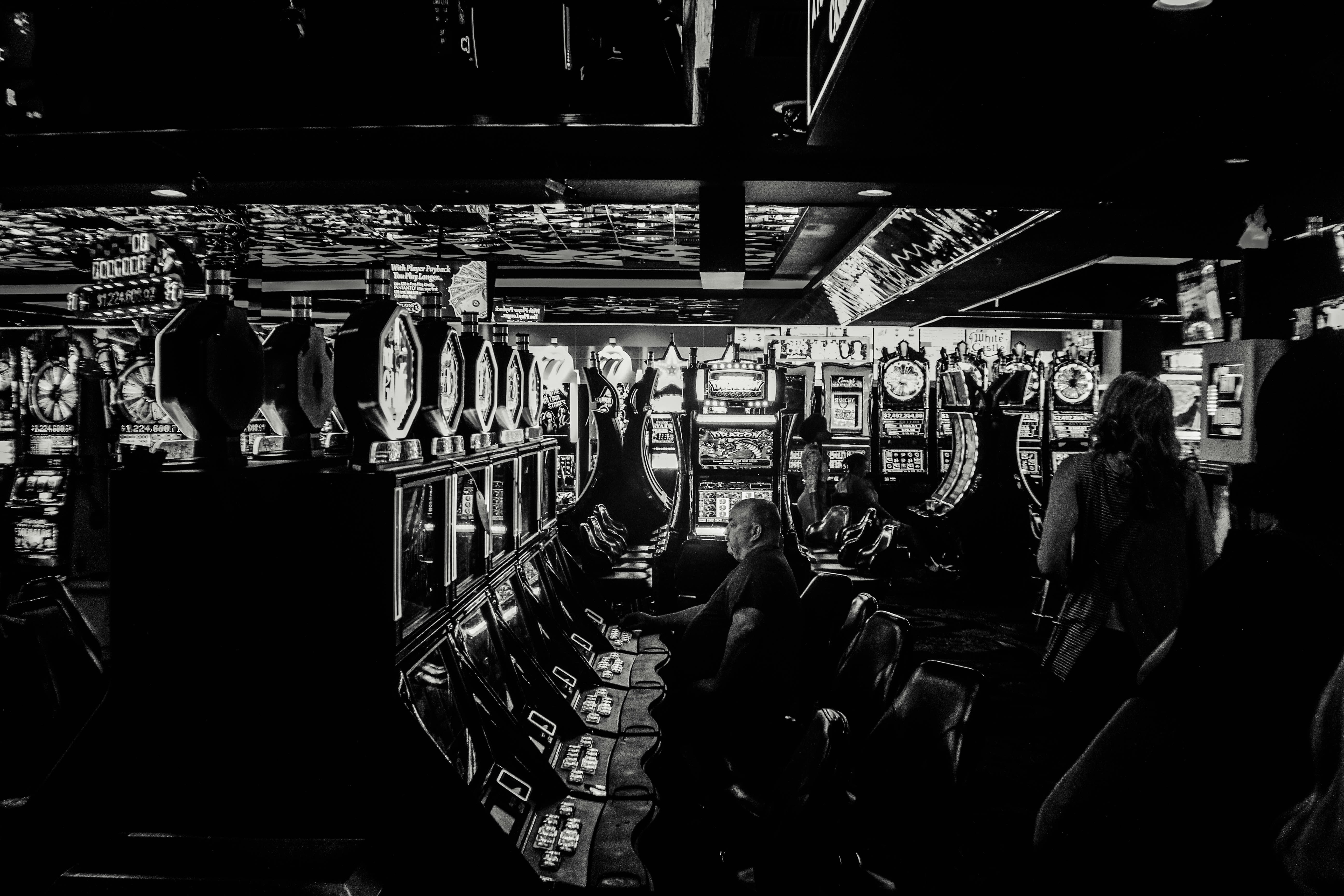 grayscale photo of man playing slot machine
