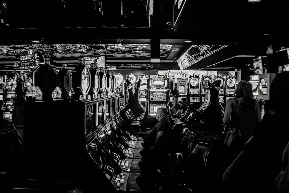 grayscale photo of man playing slot machine
