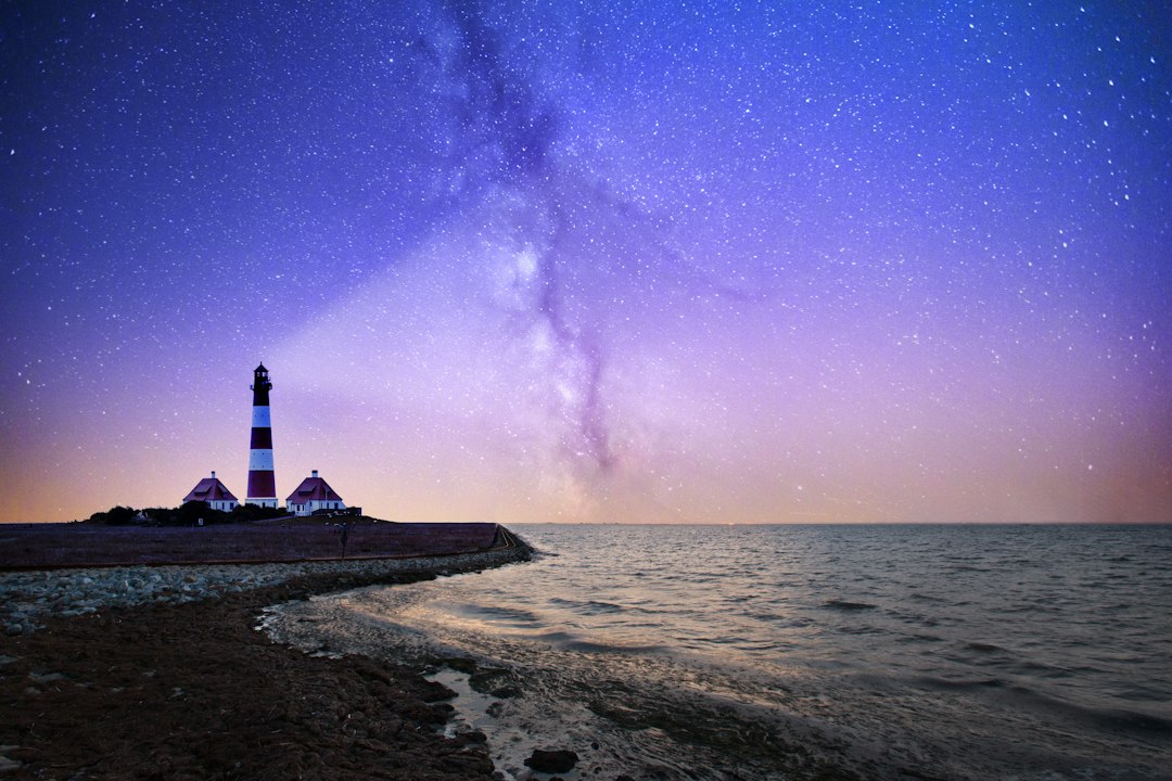 white and red lighthouse near bodies of water at night