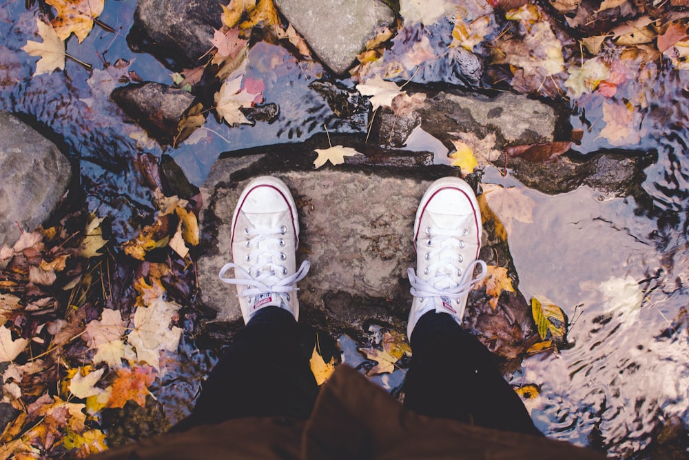 person wearing pair of white shoes standing on rock