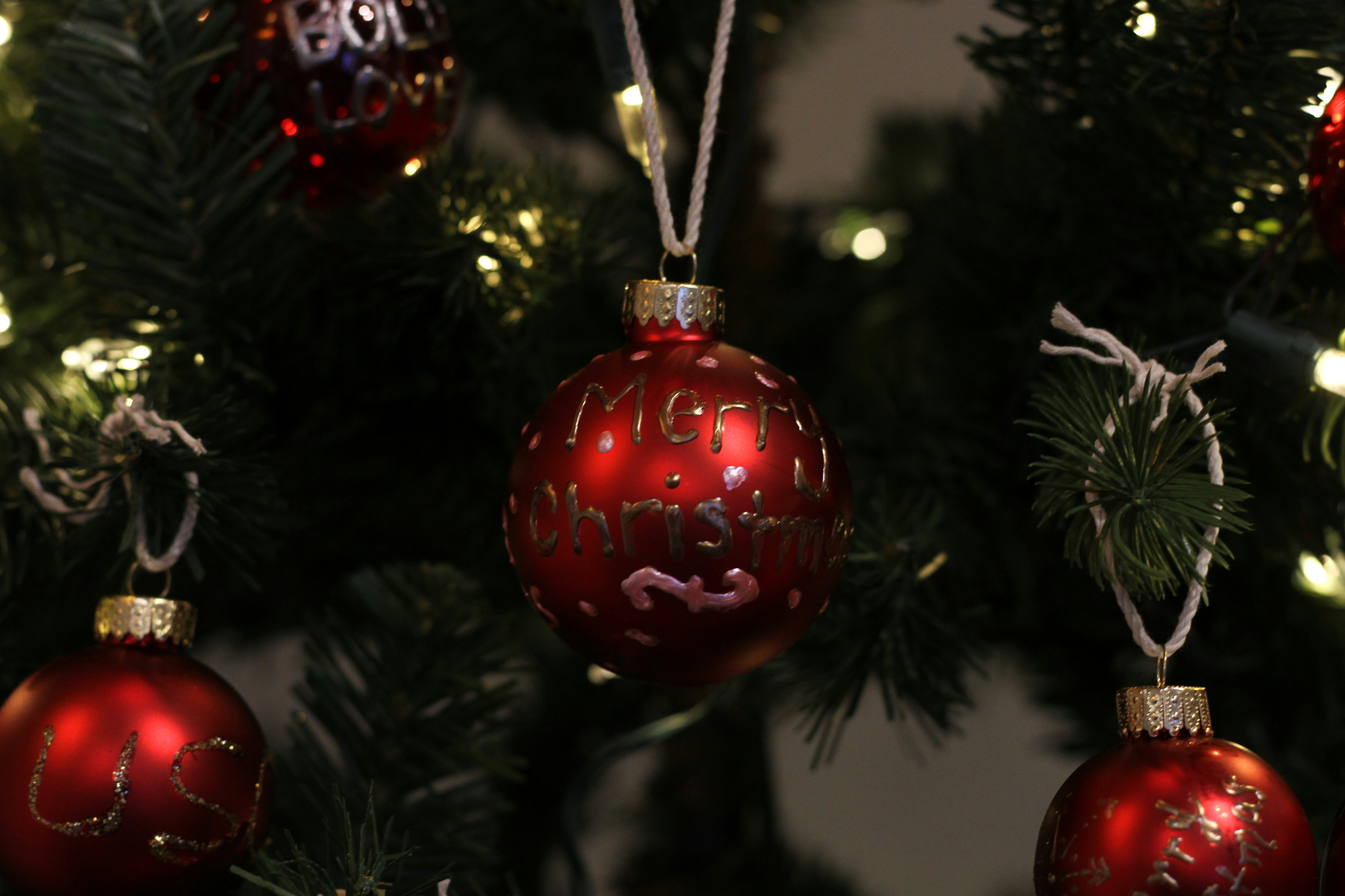 Red and gold Christmas ornaments hanging on decorated evergreen tree