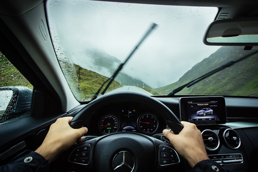 person driving Mercedes-Benz car during daytime